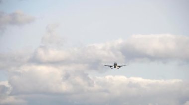 Front view of passenger jet aircraft approaching for landing against a cloudy gray sky. Tourism and aviation concept