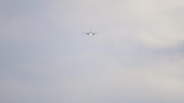 Long shot of passenger jet approaching for landing against a cloudy gray sky. Tourism and aviation concept