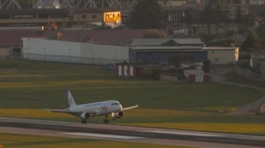 SOCHI, RUSSIA - JULY 28, 2022: Airbus A320 of Ural Airlines landing and braking at Sochi airport at sunset. Cinematic footage of the plane touching the runway. Tourism and travel concept