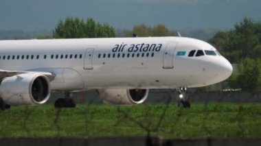 ALMATY, KAZAKHSTAN - MAY 4, 2019: Civil Airbus A320 of Air Astana taxiing on the runway at Almaty airport, side view. Mid shot, airplane on the airfield