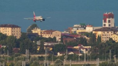 SOCHI, RUSSIA - JULY 28, 2022: Sukhoi superjet of Rossiya airlines descent for landing over the sea and the city to Sochi airport. Tourism and travel concept