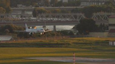 SOCHI, RUSSIA - JULY 28, 2022: Airplane of Ural Airlines landing and braking at Sochi airport at sunset. Cinematic footage of the plane touching the runway. Tourism and travel concept