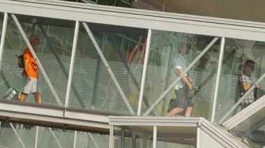 KAZAN, RUSSIA - AUGUST 05, 2022: People walking in jet bridge gangway. Airport passengers boarding on plane, view through outdoor telescopic window. Tourism and travel concept