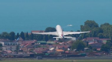 SOCHI, RUSSIA - JULY 28, 2022: Airbus A330 Nordwind takeoff and climb over the Black Sea at Sochi airport, rear view. Long shot of a passenger plane flying away