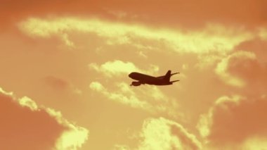 Commercial aircraft flying at sunset. Long shot of an airliner taking off gaining altitude. Cinematic footage of a jet plane in the sunset sky