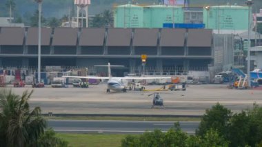 PHUKET, THAILAND - DECEMBER 1, 2016: Technical and service maintenance of Bangkok Airways aircraft, Phuket airport terminal. Helicopter on the airfield. Panoramic view of the airport apron
