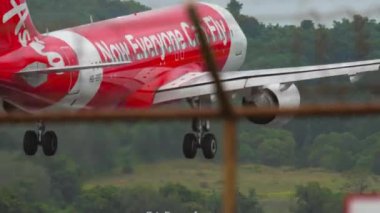 PHUKET, THAILAND - NOVEMBER 26, 2017: Airbus A320, HS-BBG of AirAsia landing, touching the runway and braking at Phuket airport. View of the strip through the fence. Tourism and travel concept