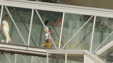 KAZAN, RUSSIA - AUGUST 05, 2022: People walking on the jet bridge gangway. Airport passengers boarding on plane, view through outdoor telescopic window. Tourism and travel concept