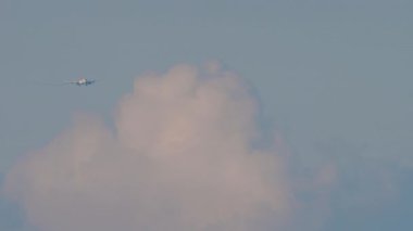 Long shot of passenger aircraft approaching to land in a cloudy sky. Airliner silhouette is flying. Tourism and air travel concept