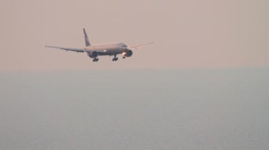SOCHI, RUSSIA - JULY 30, 2022: Boeing 777 of Aeroflot descending before landing in Sochi airport at sunset. Airliner flies over the sea and over the city. Tourism and travel concept