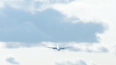Long shot rear view, jet passenger airliner flies away. Airplane taking off against the backdrop of the city in a cloudy sky. Tourism and travel concept