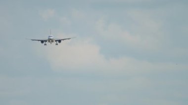 Front view of apassenger aircraft descending for landing. Jet plane approach. Airliner in the cloudy sky. Tourism and travel concept