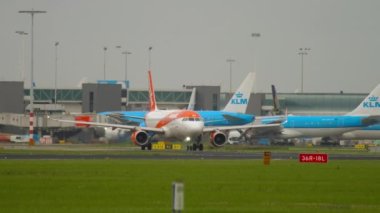 AMSTERDAM, THE NETHERLANDS - JULY 27, 2017: Airbus A320 of EasyJet rides on the taxiway to the runway at Schipol Airport, Amsterdam. In the background, the planes of the airline KLM.