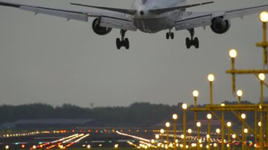 AMSTERDAM, THE NETHERLANDS - JULY 28, 2017: Boeing 777 of United landing at Schiphol Airport. Runway illuminated landing lights. United Airlines American airline. Tourism and travel concept