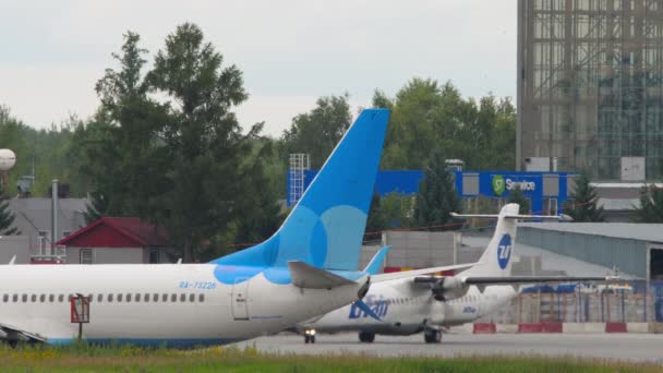 ロシア連邦ノヴォシビルスク発 2022年7月15日 トルマチェヴォ空港におけるAtr 72のUtair課税 手前のポベダ航空737型機が停まっていた 観光航空の概念 — ストック動画