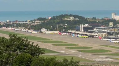 SOCHI, RUSSIA - JULY 29, 2022: Timelapse shooting at the Sochi airport, panoramic view of the airfield. Takeoffs and landings of aircraft during the daytime. Black Sea in the background