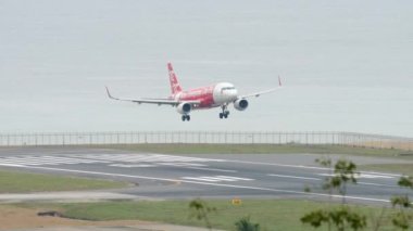 PHUKET, THAILAND - NOVEMBER 28, 2017: Low-cost airline Airbus A320 of AirAsia airline landing and braking at Phuket airport. Airliner on the background of the sea. Tourism and travel concept