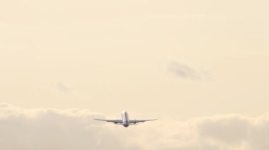 Long shot of a passenger plane climbing after takeoff. Airplane silhouette at sunset or sunrise