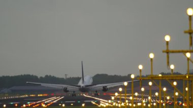 Cinematic footage of a commercial passenger plane landing. Runway brightly lit with landing lights. Tourism and travel concept