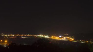 Timelapse, night view of the airport and traffic. Landing lights illuminate the runway