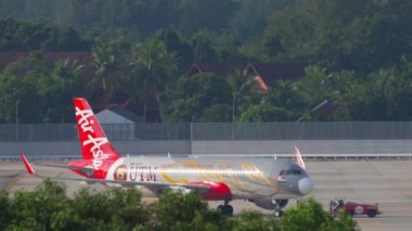 PHUKET, THAILAND - NOVEMBER 29, 2019: Tractor towing Airbus A320, 9M-AJE of AirAsia Universiti Teknologi Malaysia Livery to the terminal at Phuket airport