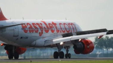 AMSTERDAM, THE NETHERLANDS - JULY 26, 2017: Passenger airplane Airbus A320 of EasyJet arrival at Schiphol Airport. Airplane braking on the runway, medium shot. Tourism and travel concept