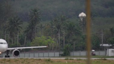 PHUKET, THAILAND - DECEMBER 1, 2016: Passenger plane of AirAsia taxiing at Phuket airport. View of the plane through the fence of the airport. Airliner on the airfield of a tropical island