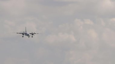 Turboprop unrecognizable aircraft in the sky approaching for landing, long shot. Civil passenger plane flies in the early morning