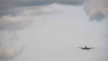 Jet passenger airplane approaching to land, front view. Cloudy sky, the airliner is flying