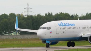 NOVOSIBIRSK, RUSSIAN FEDERATION - JULY 15, 2022: Side view, Boeing 737 of Pobeda Air taxiing on the runway at Tolmachevo airport, Novosibirsk. Tourism and travel concept