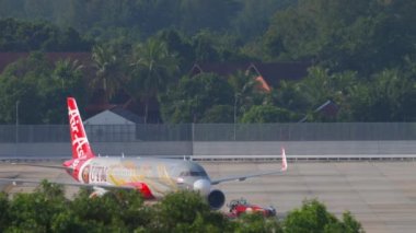 PHUKET, THAILAND - NOVEMBER 29, 2019: Tractor pulls Airbus A320 of AirAsia at Phuket airport. Asian low-cost airline on the airfield. Tourism and travel concept