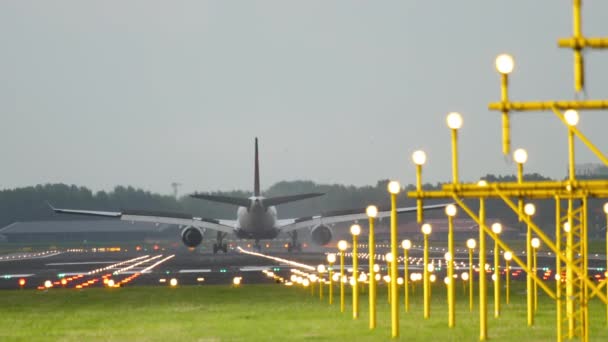 後部ビュー ジェット飛行機が到着 滑走路灯で光る 着陸後に上昇したフラップでブレーキ 観光と旅行のコンセプト — ストック動画