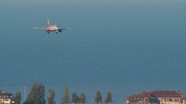SOCHI, RUSSIA - JULY 28, 2022: Sukhoi superjet of Rossiya airlines descent for landing over the sea and the city to Sochi airport. Tourism and travel concept