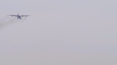 Turboprop military aircraft turboprop approaching to land, long shot. Heavy transport four-engine aircraft in the sky