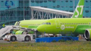 NOVOSIBIRSK, RUSSIAN FEDERATION - JULY 15, 2022: Tugboat towing aircraft of S7 Airlines on the runway at Tolmachevo airport. Tourism and travel concept