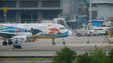 PHUKET, THAILAND - NOVEMBER 30, 2016: Airbus A320 Bangkok Air on the platform of Phuket airport, side view. Tractor, ladder mobile ladder and airport workers on the apron