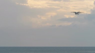 Turboprop aircraft approaching to land over the sea, long shot side view