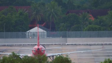 Unrecognizable Airliner taxiing on the airfield, rear view. Palm trees in the background
