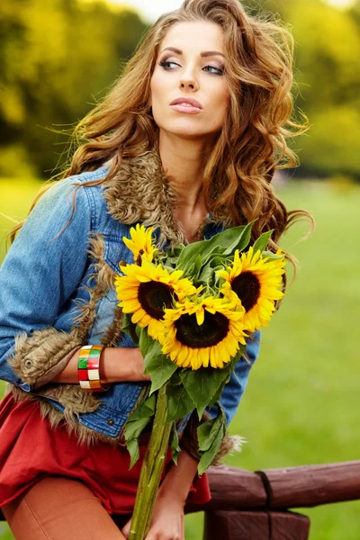 Giovane donna di moda con un mazzo di girasoli nel campo — Foto Stock