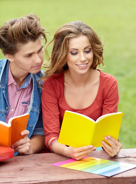 Un par de estudiantes sosteniendo un cuaderno al aire libre y sonriendo — Foto de Stock