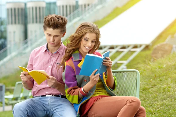Casal de alunos com sentado no parque do campus e livro de leitura — Fotografia de Stock