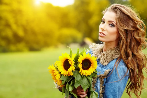 Jeune femme de mode avec un bouquet de tournesols dans le domaine — Photo