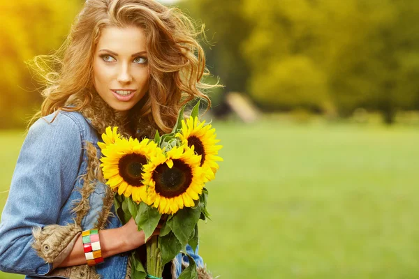 Jonge mode vrouw met een boeket van zonnebloemen in het veld — Stockfoto