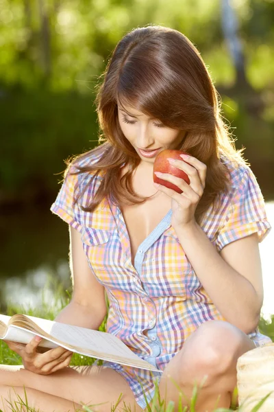 Mujer manzana. Muy hermosa modelo comiendo manzana roja en el parque . — Foto de Stock