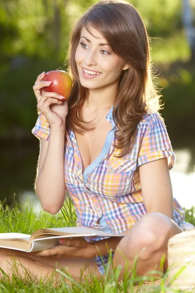 Mujer manzana. Muy hermosa modelo comiendo manzana roja en el parque . —  Fotos de Stock