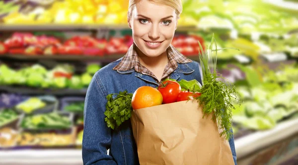 Vacker ung kvinna med grönsaker och frukter i shopping väska — Stockfoto