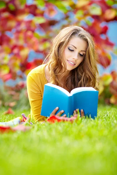 Menina bonita com livro no parque de primavera — Fotografia de Stock