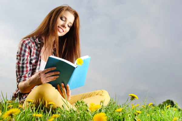 Beautiful girl lies on meadow and reads the boo — Stock Photo, Image