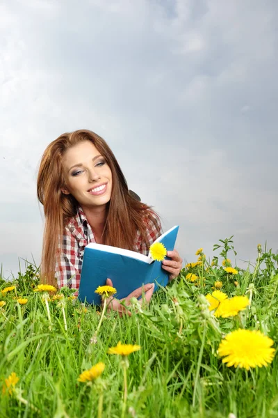 美しい少女は牧草地に位置し、ブーイングを読み取ります — ストック写真