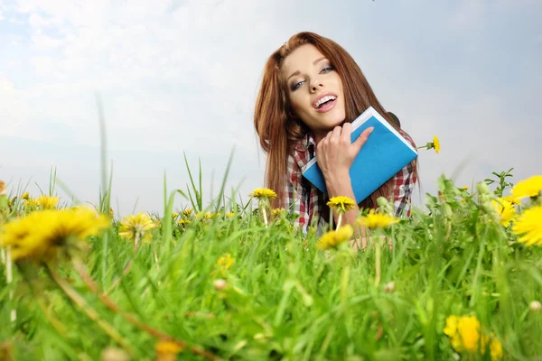 Menina bonita com livro na grama — Fotografia de Stock